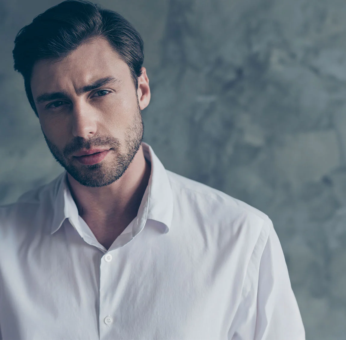 thoughtful man in a white dress shirt with a grey background - Laser Skin Resurfacing at HIM Plastic Surgery