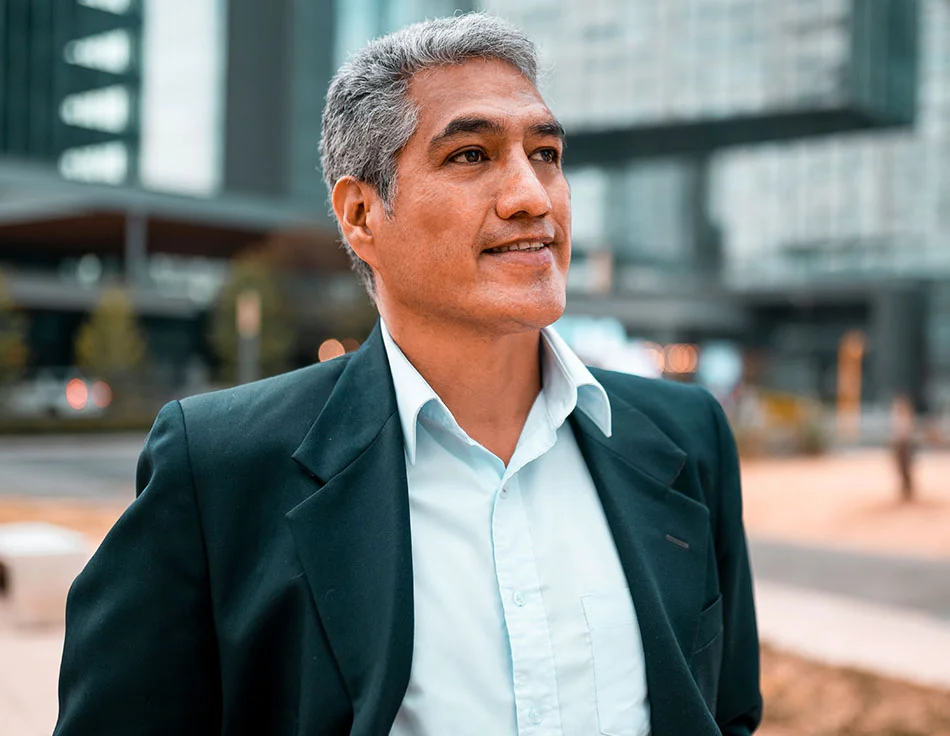 A man with grey hair, wearing a white button up and a suit, looking up - Revision Facelift at HIM Plastic Surgery