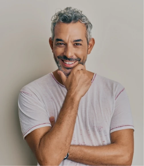 gray haired man with hand under chin smiling HIM plastic Surgery In Dallas, TX