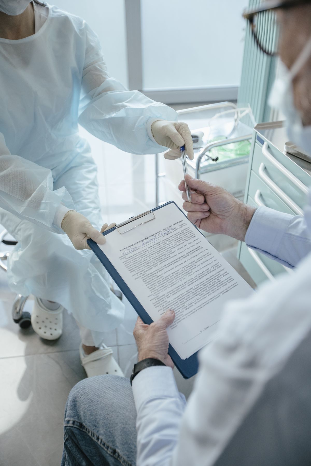 Patient in a medical office receiving documents to review and sign from a healthcare professional